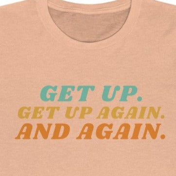 Peach Tee shirt with colorful wording: Get up, Get up again and again.